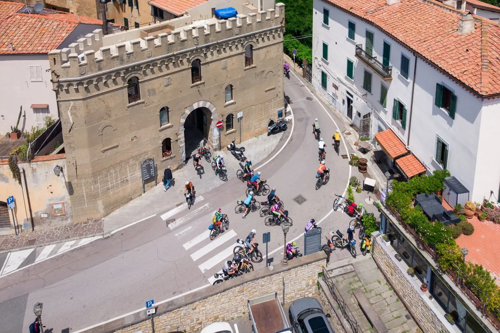 Il borgo di Campiglia Marittima dall'alto, con il gruppo del Tuscany Trail che passa sotto la porta